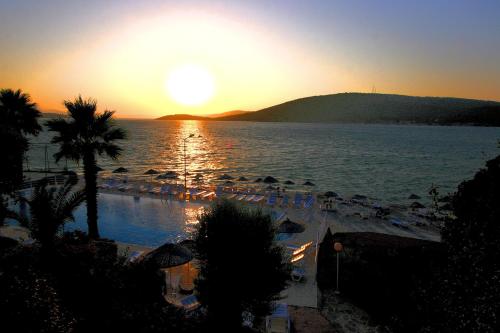 a view of a beach with the sun setting over the water at Greenport Bodrum Hotel in Guvercinlik