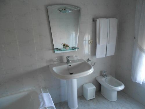 ein weißes Bad mit einem Waschbecken und einem WC in der Unterkunft Habitaciones Ninfa in Villalonga