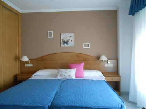 a bedroom with a blue bed with pink pillows at Habitaciones Ninfa in Villalonga