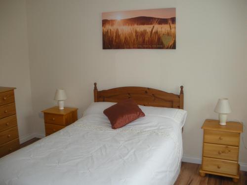 a bedroom with a white bed with two night stands and two lamps at Beautiful 3-Bed House in Knock in Knock