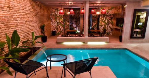 basen z krzesłami, stołem i ścianą z cegły w obiekcie Oasis Fresh Hotel w mieście Santa Marta