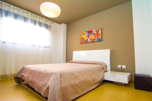 1 dormitorio con cama y ventana en Apartamentos 16:9 Playa Suites, en Almería