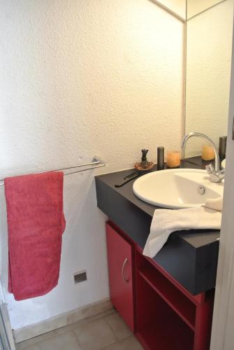 une salle de bain avec un lavabo et une serviette rouge dans l'établissement Résidence Goélia Sun Village, à Portiragnes