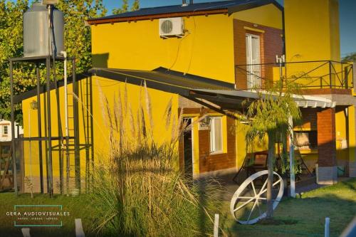 Una casa amarilla con un carro delante. en Cabañas bajos medanales en Victorica