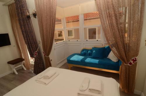 a bedroom with a blue couch and a window at Grand Alaçatı Butik Hotel in Alacati