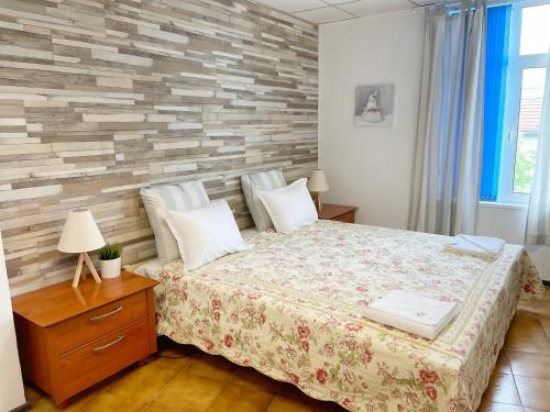 a bedroom with a bed and a brick wall at Апартамент Компас in Burgas City