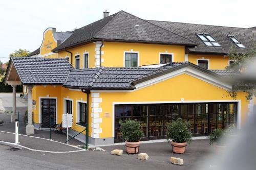a yellow building with a black roof at Perbersdorfer Heuriger in Neuhofen an der Ybbs