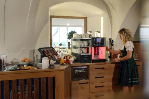 a woman standing in a kitchen with a coffee maker at Perbersdorfer Heuriger in Neuhofen an der Ybbs