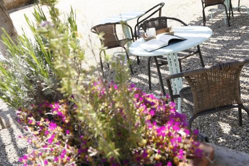 a patio with tables and chairs and purple flowers at Hort de L'Aubert in Cretas