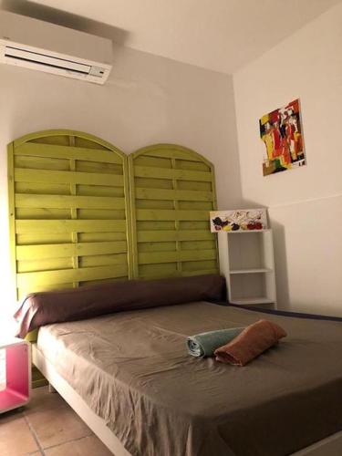 une chambre avec un grand lit avec une tête de lit verte dans l'établissement U riposu, à Bastia