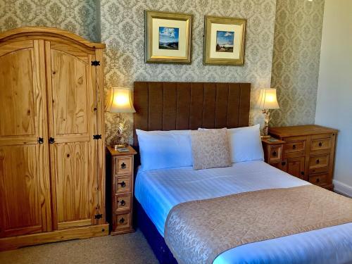 a bedroom with a bed and a cabinet and two lamps at Balmoral in Skegness