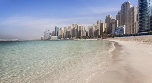 a beach in front of a city with tall buildings at Stunning 5* 4BR-Oceanfront-Apartment in Dubai
