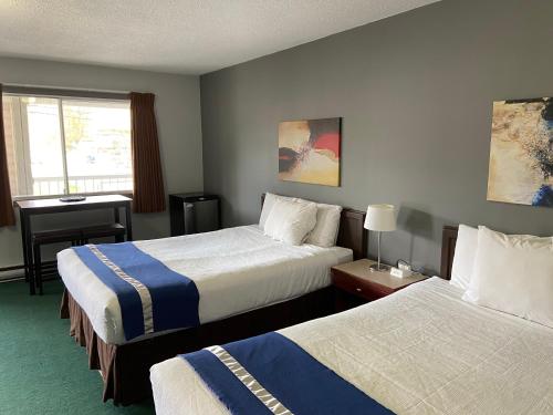 a hotel room with two beds and a window at Monashee Lodge in Revelstoke
