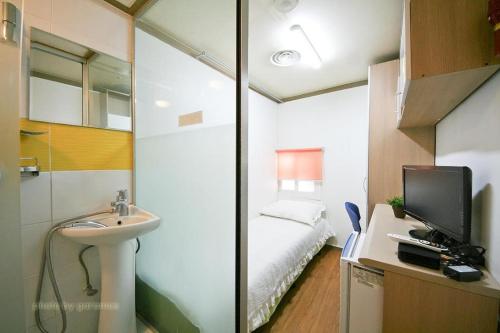 een badkamer met een wastafel en een slaapkamer met een bed bij Rodemhouse in Seoul