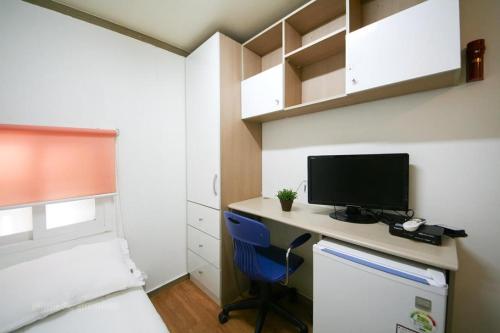 een slaapkamer met een bureau, een computer en een bed bij Rodemhouse in Seoul