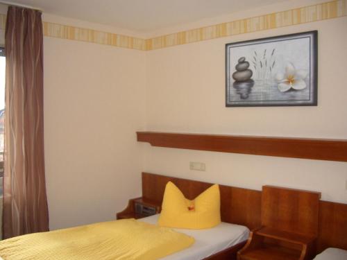 ein Schlafzimmer mit einem Bett und einem gelben Kissen in der Unterkunft Hotel Battenfeld in Plettenberg