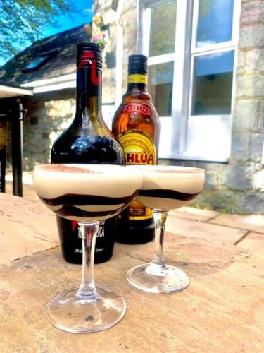 two bottles of alcohol and two wine glasses on a table at The Heights Bunkhouse in Llanberis