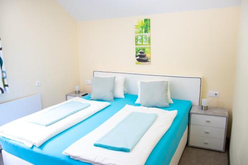 a blue and white bed with two pillows on it at Strandhotel Burgstaller in Feld am See
