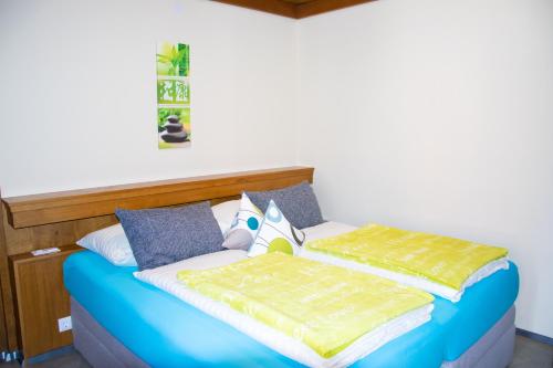 a bedroom with a bed with blue and yellow sheets at Strandhotel Burgstaller in Feld am See