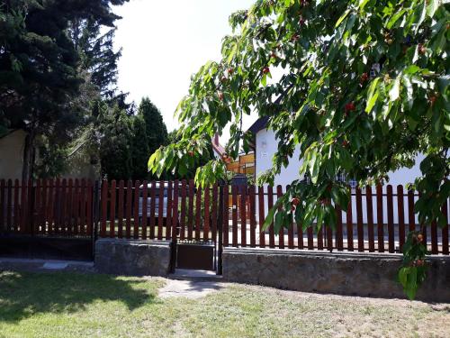 een houten hek met een boom ervoor bij Szilva Apartman in Fertőhomok