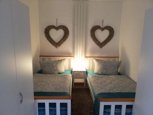 dwa łóżka w pokoju z sercami na ścianie w obiekcie Ferienwohnung Kleines Nest w mieście Hohendodeleben
