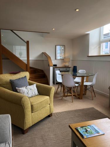 a living room with a yellow couch and a table at The Old English Rooms in Falmouth