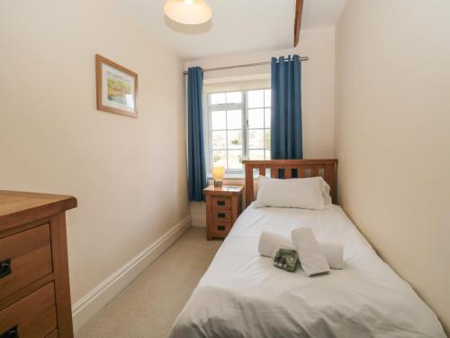 a small bedroom with a bed and a window at The Old School House in Hutton le Hole