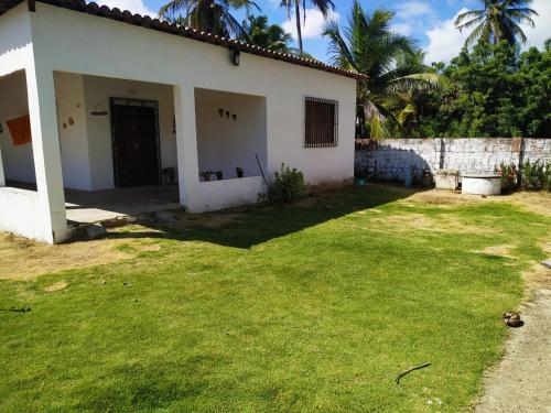 a white house with a grass yard next to a building at Doce Lar - Casa de Praia in Itapipoca