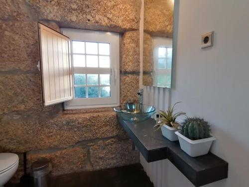 ein Bad mit einem Waschbecken und einem Fenster in der Unterkunft Casa antiga de pedra com piscina e vista rio in Amarante