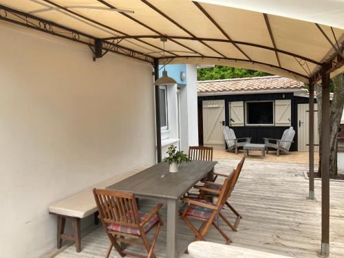 un patio avec une table et des chaises en bois dans l'établissement Studio CAP-OCEAN cap ferret, à Cap-Ferret