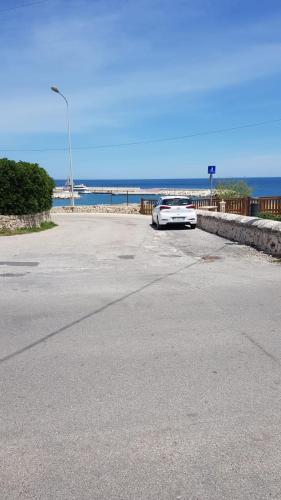 a white car parked on a road near the ocean at Casa dei sospiri in Polignano a Mare