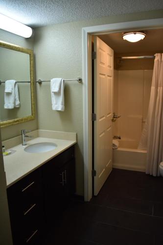 a bathroom with a sink and a mirror and a tub at Staybridge Suites Cranbury - South Brunswick by IHG in Cranbury