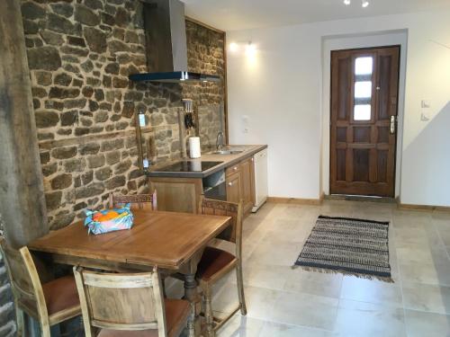 cocina con mesa de madera y pared de piedra en Les Maricotais Gîte L'Hirondelle en Trévérien