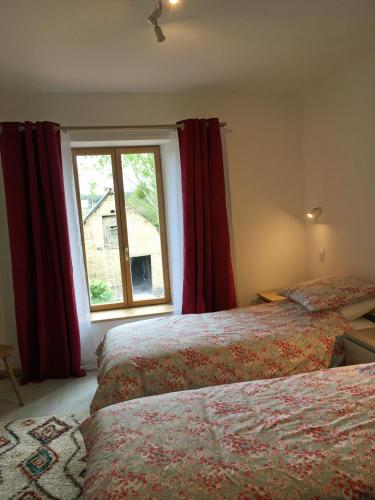 - une chambre avec 2 lits et une fenêtre avec des rideaux rouges dans l'établissement Les Maricotais Gîte L'Hirondelle, à Trévérien