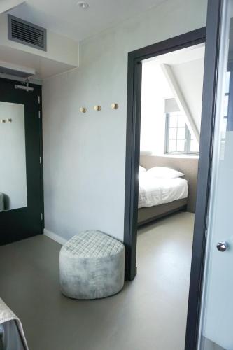 a bedroom with a mirror and a ottoman and a bed at "Het Wapen Van Willemstad" in Willemstad