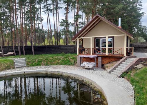 a small house with a pond in front of it at Комплекс На Дачі in Vyshpolʼ