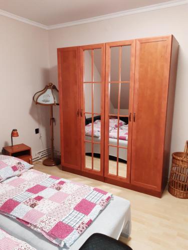 um quarto com um armário de madeira ao lado de uma cama em Boglárka Apartman em Gyula