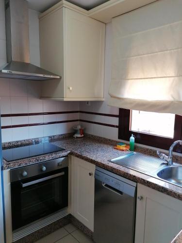 a kitchen with white cabinets and a sink and a dishwasher at The Apartment in Gran Tarajal