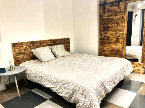a bedroom with a bed with a wooden headboard and a table at Studio cocooning Spa, lit XXL, cour extérieure in Le Puy en Velay
