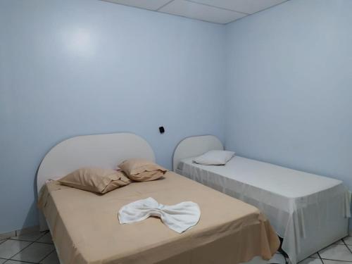 two beds in a room with a white wall at HOTEL GARCIA in Várzea Grande