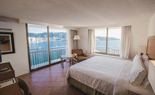 a hotel room with a bed and a view of the water at Holiday Inn Resort Acapulco, an IHG Hotel in Acapulco