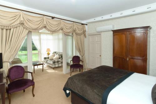 a bedroom with a bed and two chairs and a couch at Flitwick Manor Hotel in Flitwick