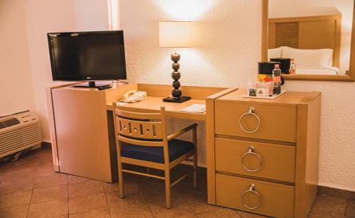a desk with a television and a lamp at Holiday Inn Resort Acapulco, an IHG Hotel in Acapulco