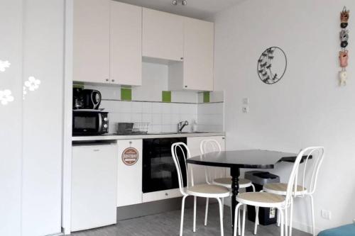 une cuisine avec une table et des chaises et un micro-ondes dans l'établissement STUDIO 150M DE LA PLAGE DES DEMOISELLES, à Saint-Hilaire-de-Riez