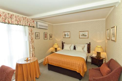 a hotel room with a bed and two chairs at Flitwick Manor Hotel in Flitwick