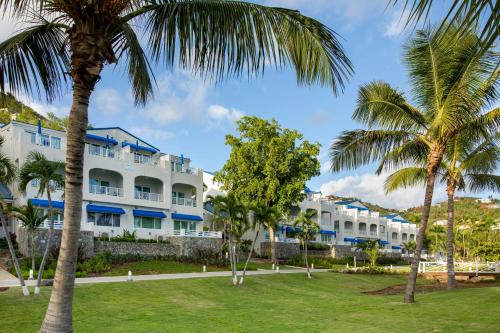 un gran edificio blanco con palmeras en el primer plano en Limetree Beach Resort by Club Wyndham, en Raphune