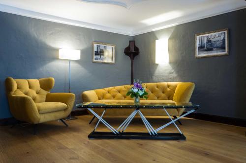 a living room with a yellow couch and two chairs at Altstadt Hotel Stadtkrug in Salzburg