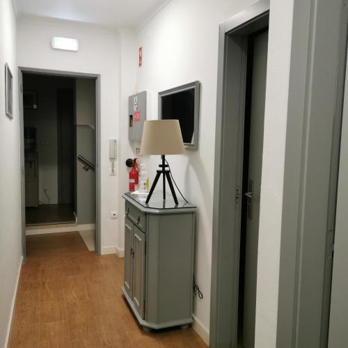 a hallway with a lamp on a dresser and two doors at Flor da Primavera - Residencial e Apartamentos in Azambuja
