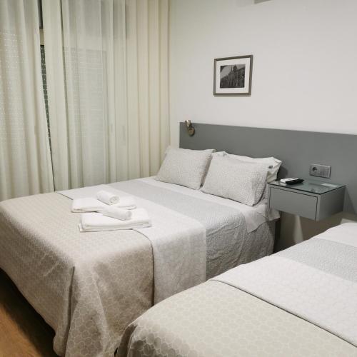 two beds in a hotel room with towels on them at Flor da Primavera - Residencial e Apartamentos in Azambuja