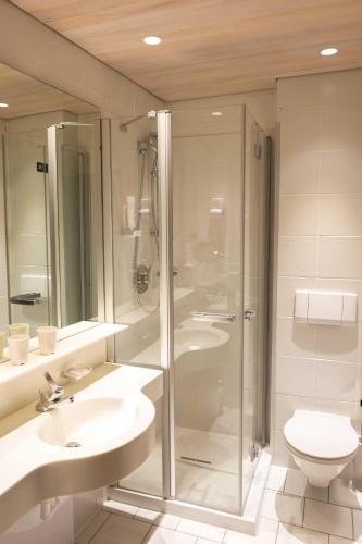 a bathroom with a shower and two sinks and a toilet at Altstadt Hotel Stadtkrug in Salzburg